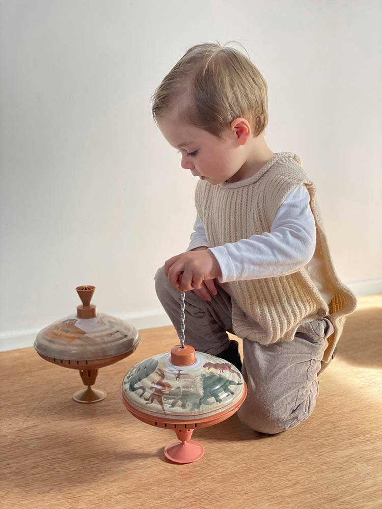 A young child plays with old-fashioned metal toy tops