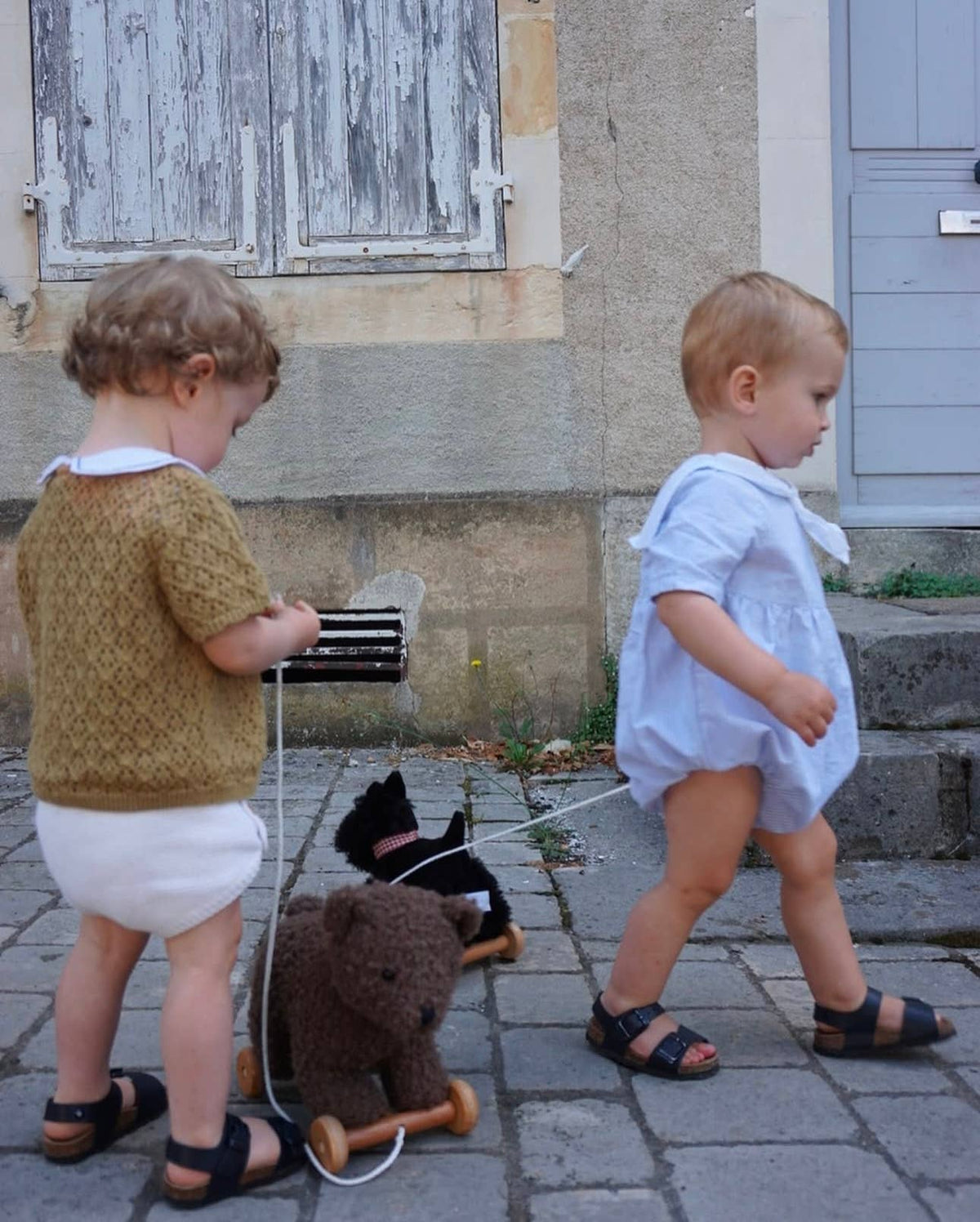 Two young children playing outside in adorable outfits.