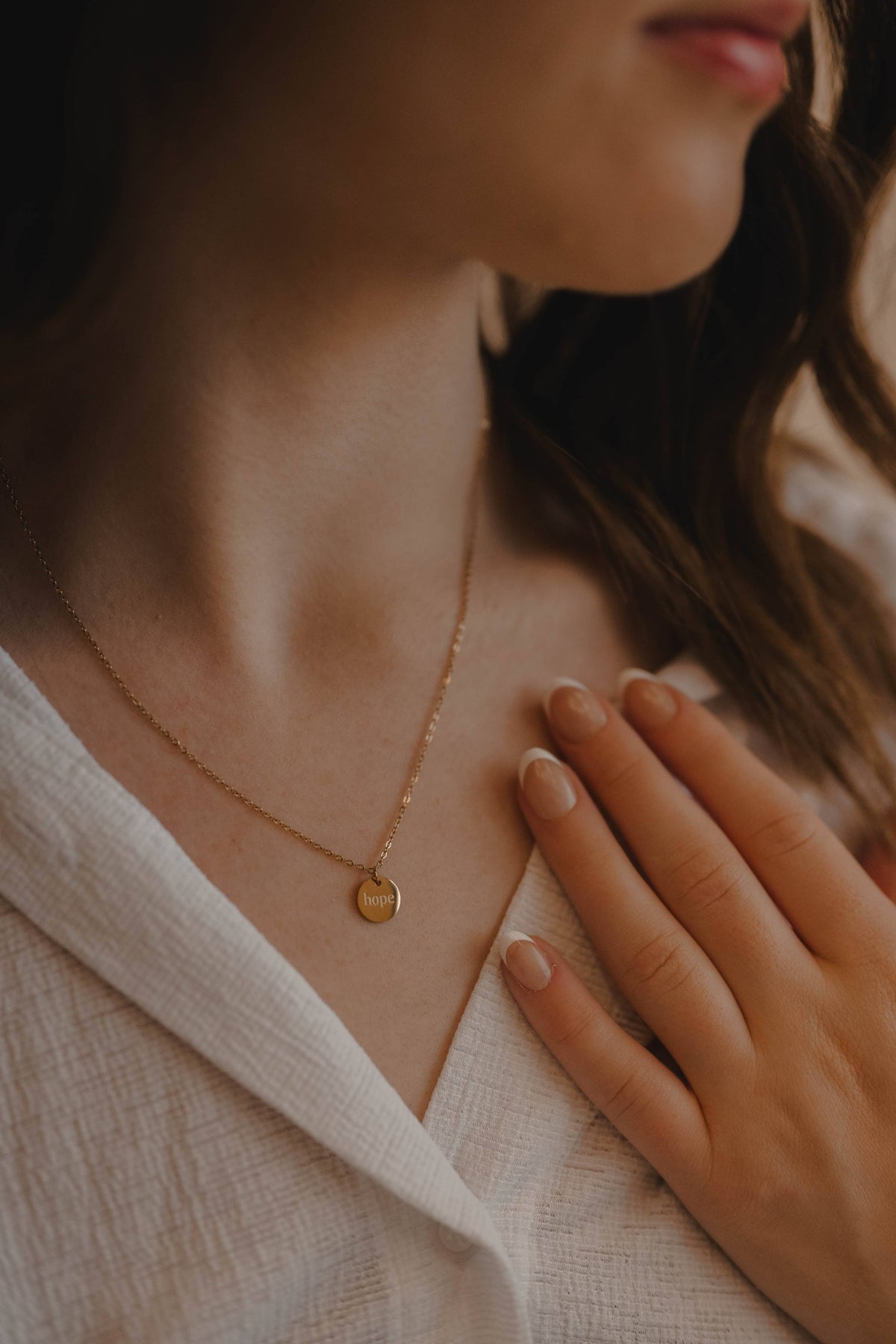 Close-up of a person wearing a delicate gold necklace with a small pendant.