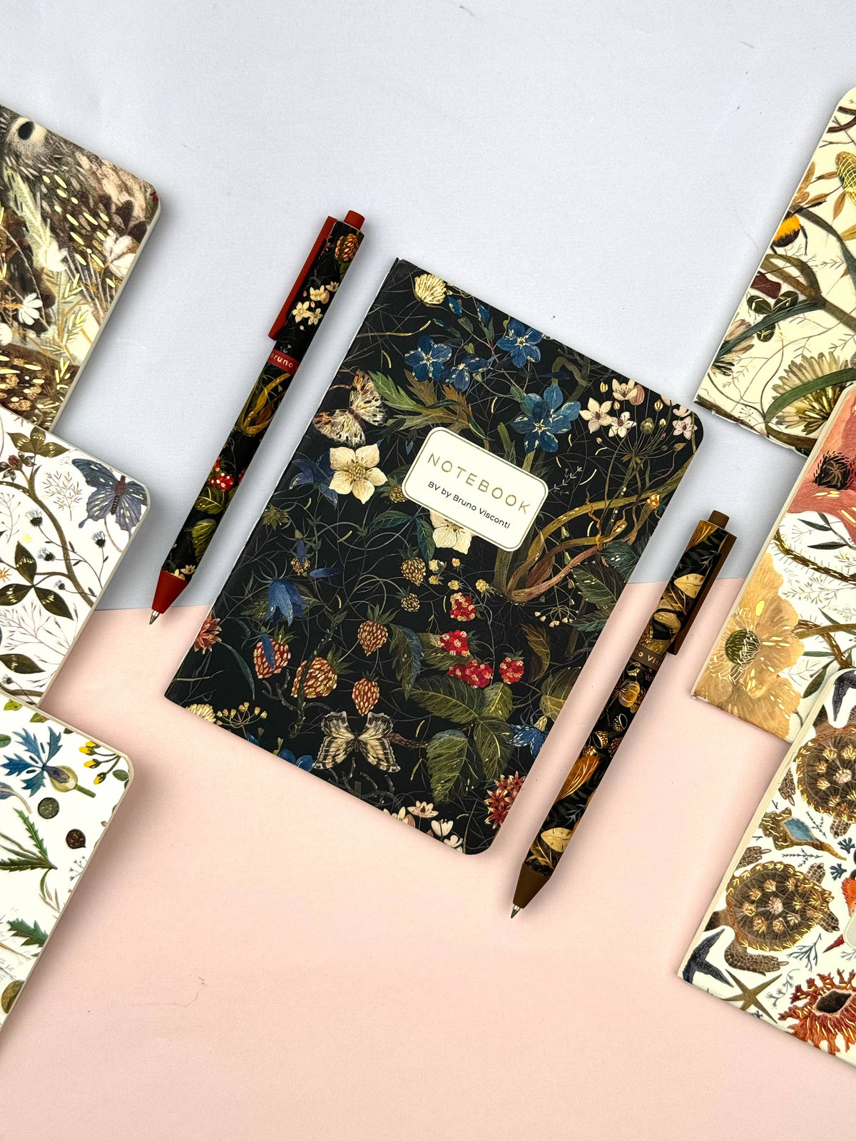 Floral notebook with pens on a colored background
