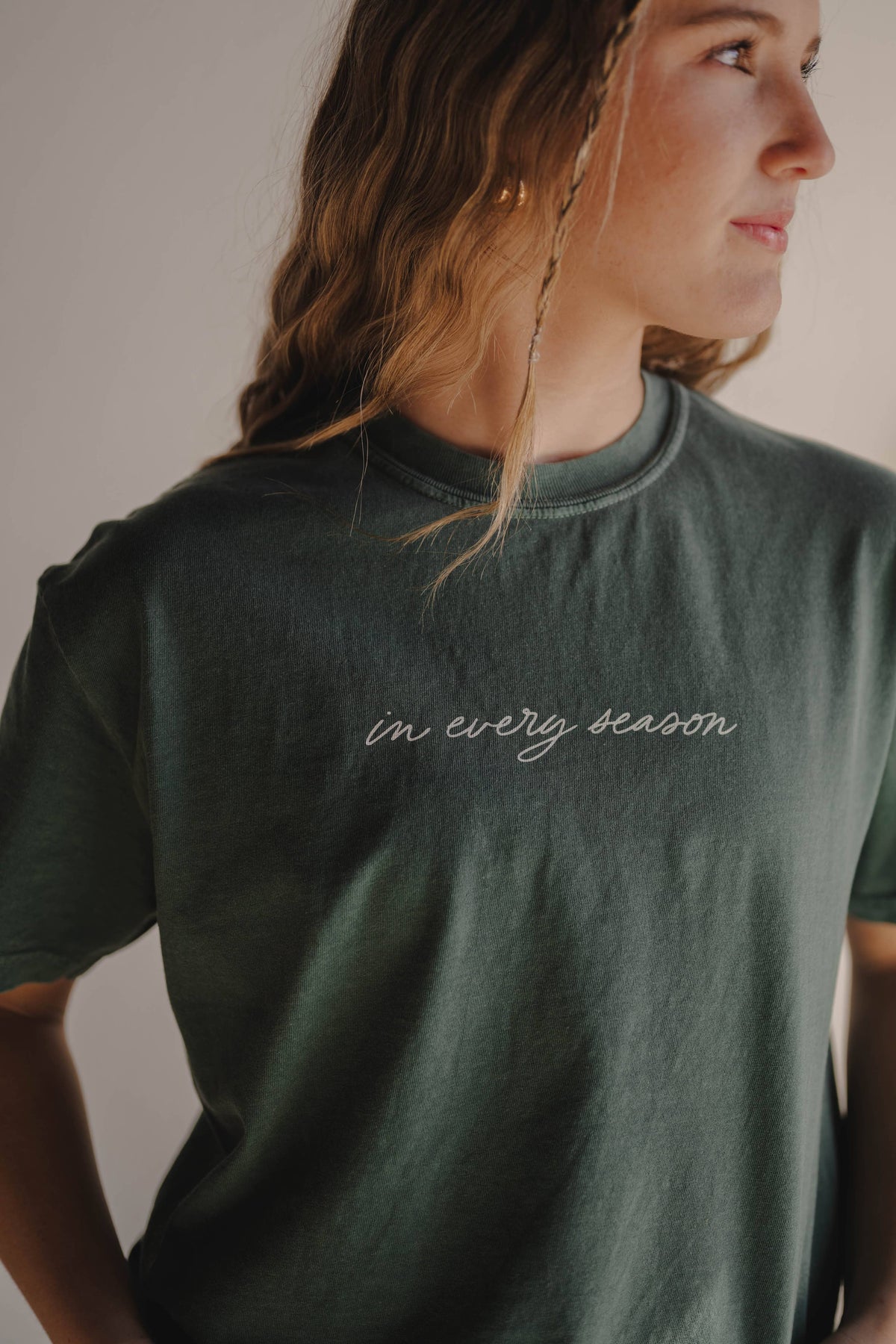 Person wearing a green t-shirt with 'in every season' text.