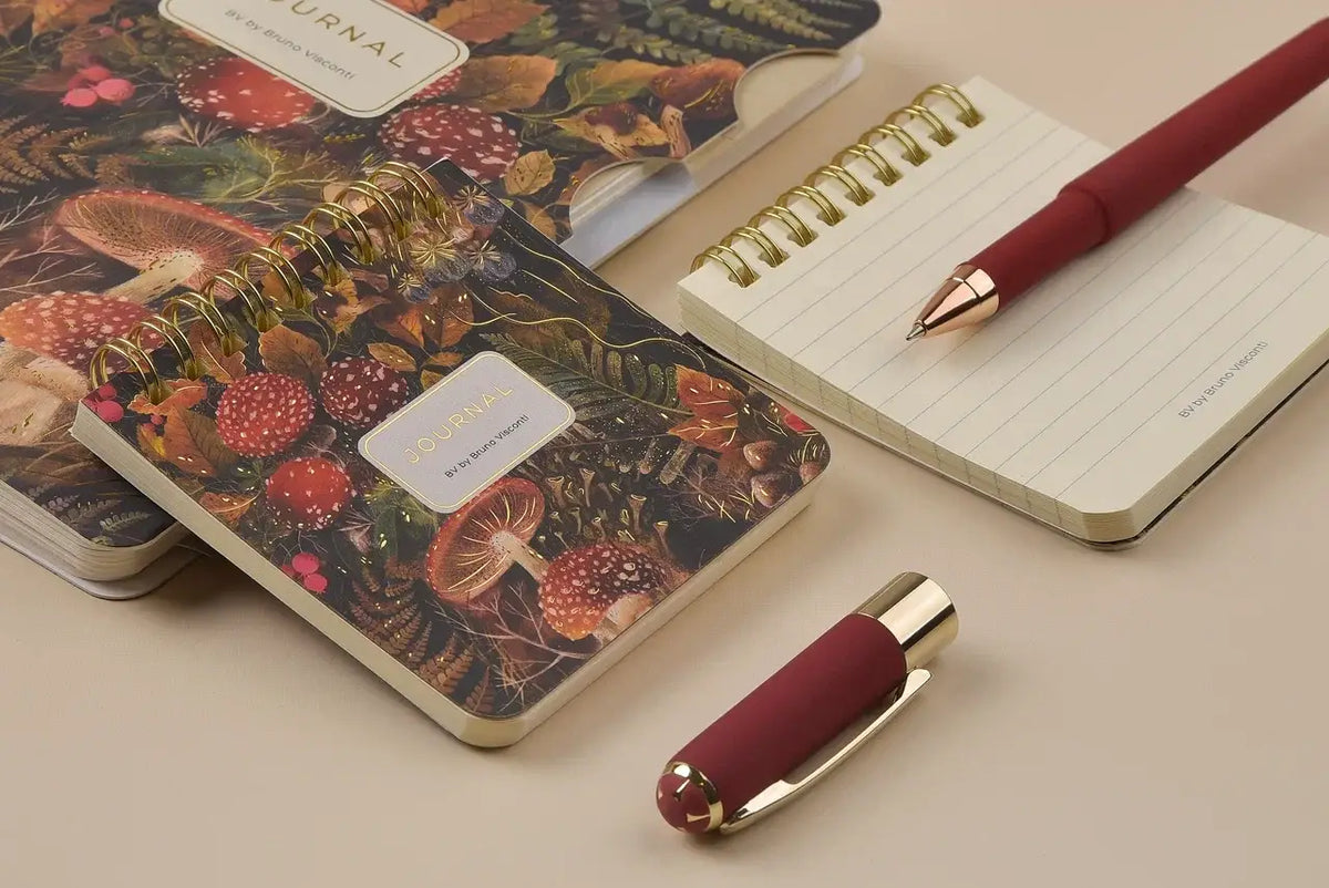 Notebook with a mushroom design cover, pen, and decorative item on a beige surface